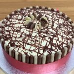 Milk and white chocolate cake decorated with chocolate buttons and chocolate fingers